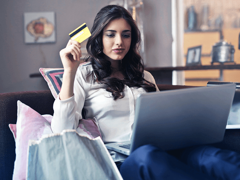 Mulher com um cartão de crédito na mão prestes a fazer uma compra online